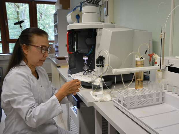 Mitarbeiterin sitzt vor Analysegerät im Labor